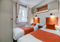 Modern twin bedroom with orange accents and two single beds