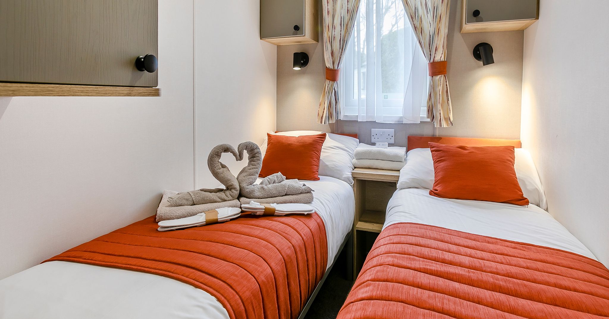 Cozy twin bedroom with orange accents and swan-shaped towels