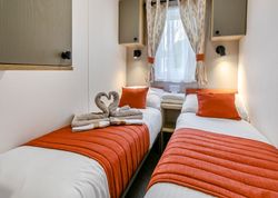 Cozy twin bedroom with orange accents and swan-shaped towels