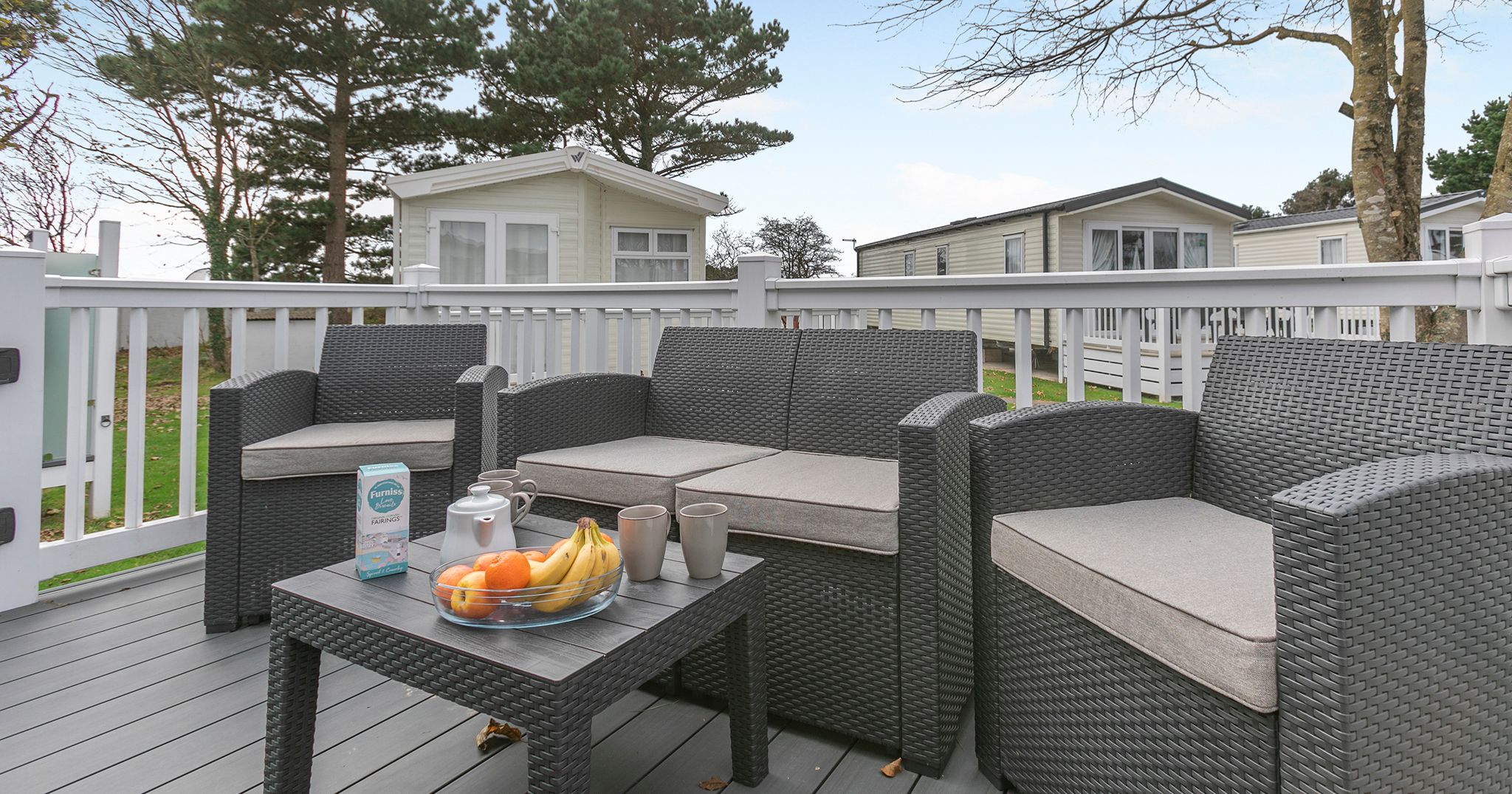 Outdoor deck with rattan furniture and coffee table beside mobile homes