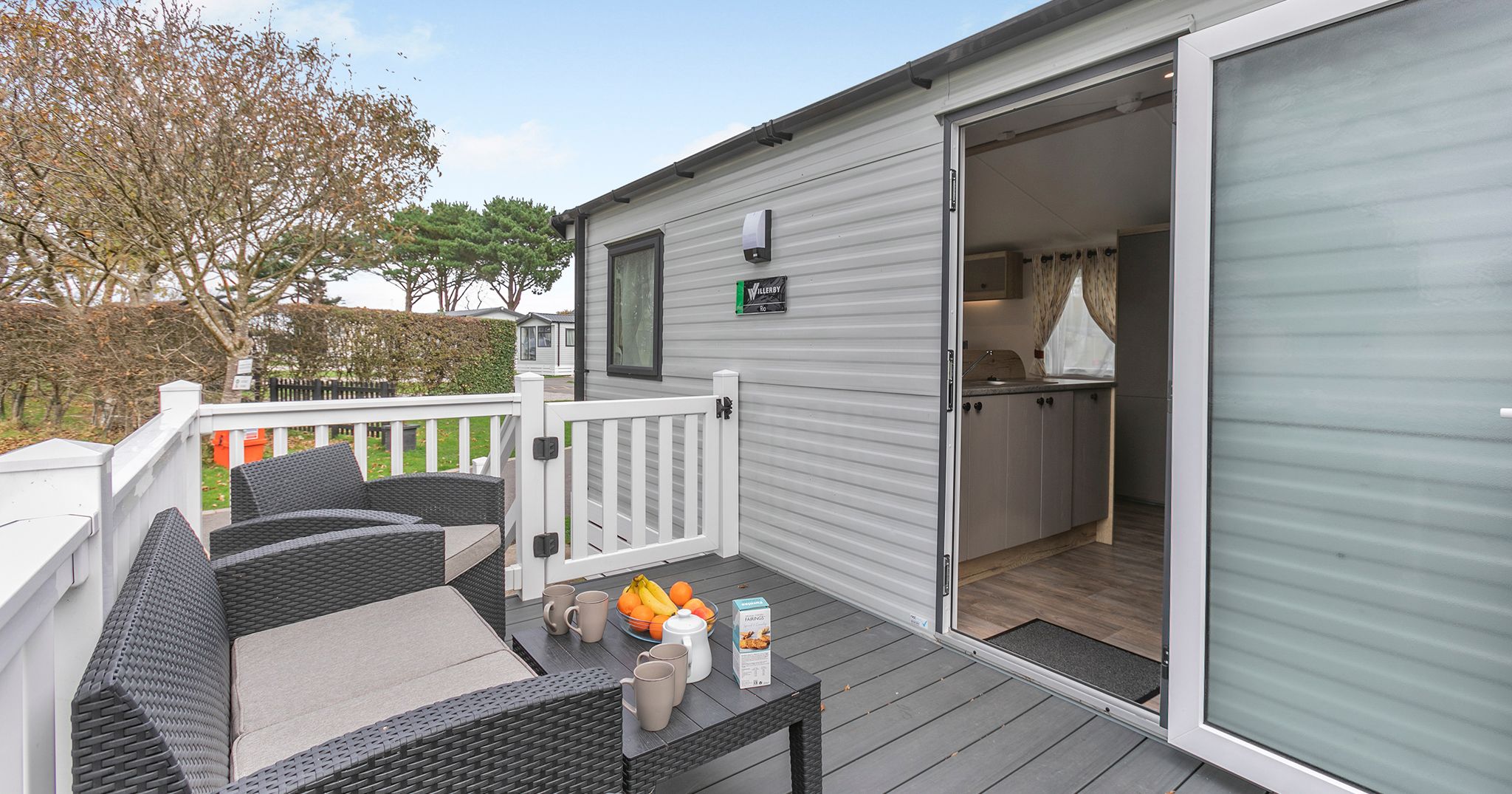 Outdoor seating area and entrance to a mobile home with open door.