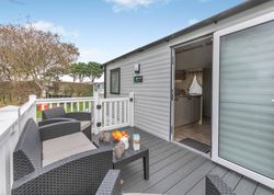 Outdoor seating area and entrance to a mobile home with open door.