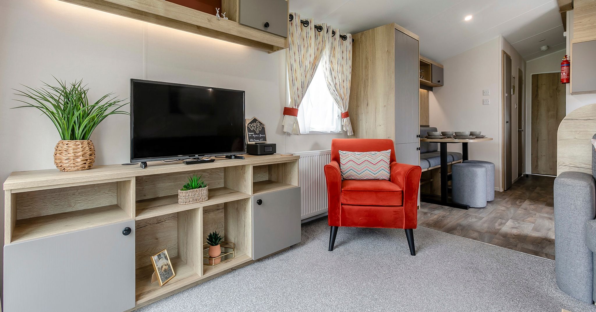 Modern living room with red armchair, TV, and wood furnishings