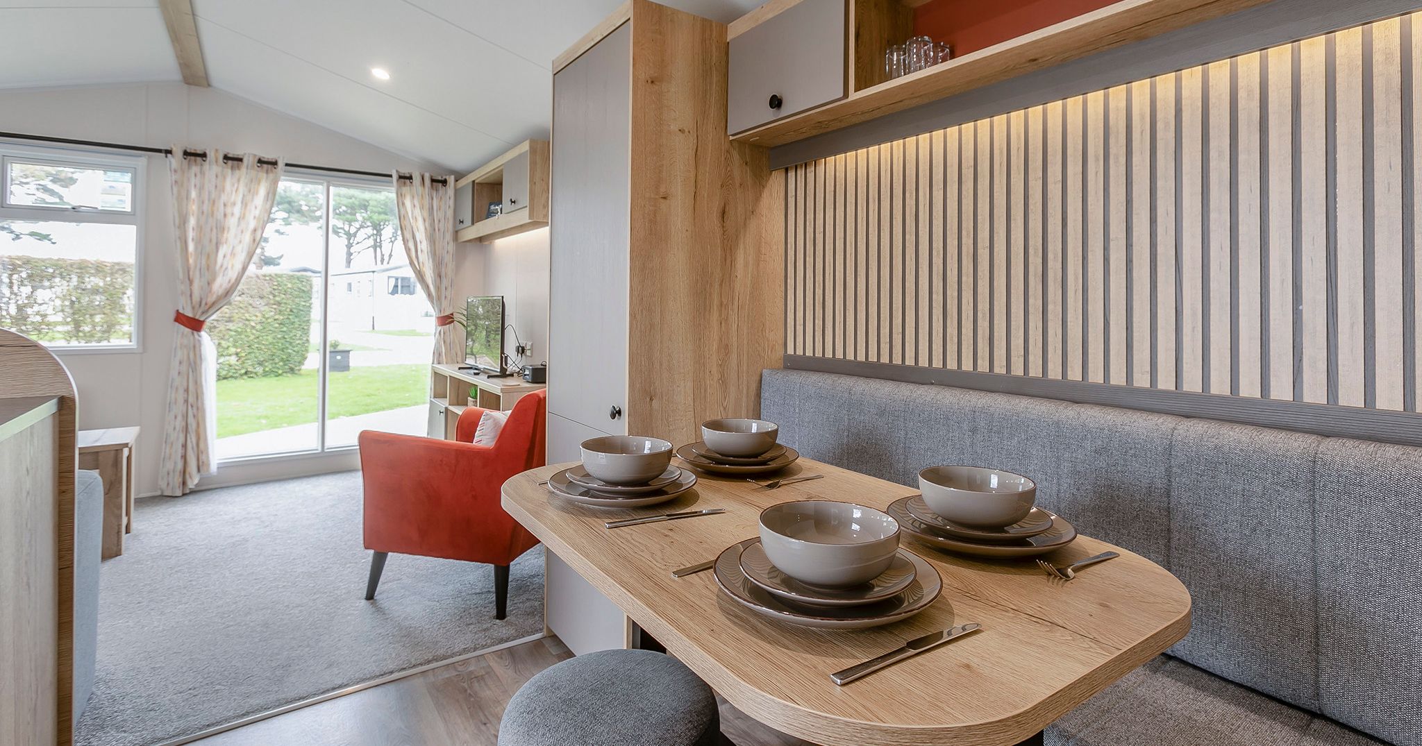 Modern mobile home dining and living area with table set for four and view of outside greenery