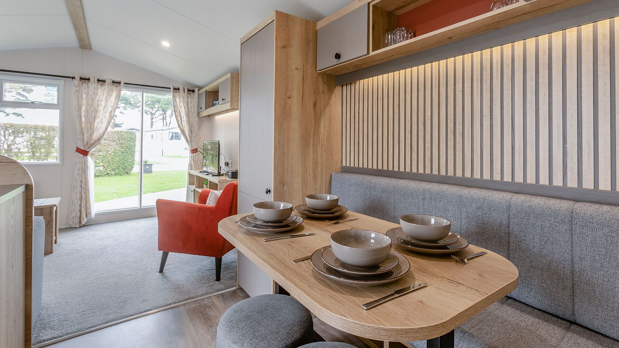 Modern mobile home dining and living area with table set for four and view of outside greenery