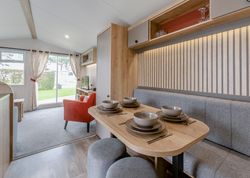 Modern mobile home dining and living area with table set for four and view of outside greenery
