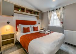 Modern bedroom with orange accents and neatly made bed