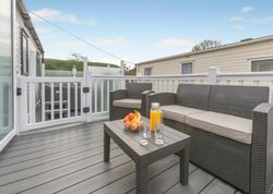 Outdoor patio with rattan furniture, a bowl of fruit, orange juice, and glasses on a table