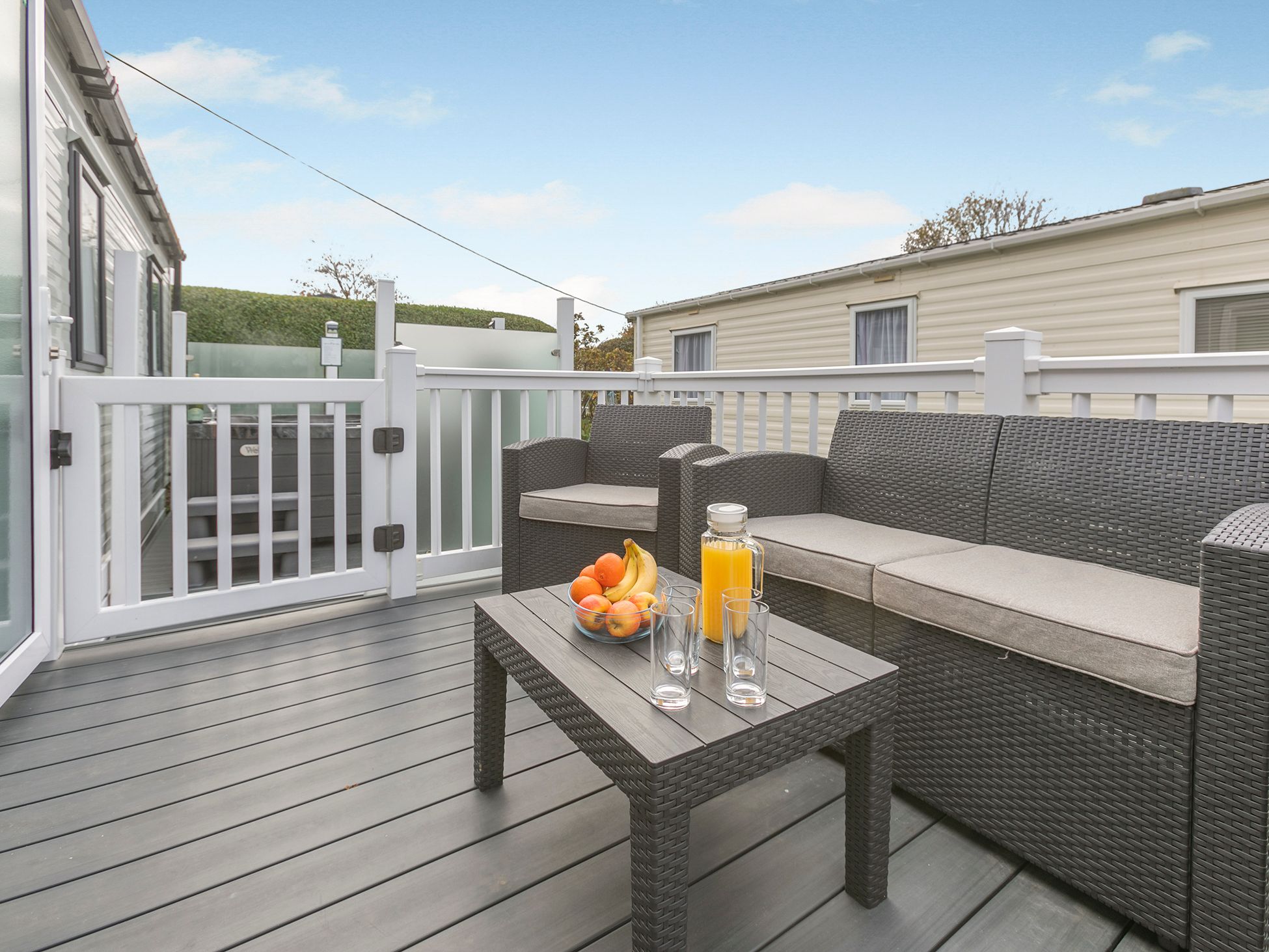 Outdoor patio with rattan furniture, a bowl of fruit, orange juice, and glasses on a table