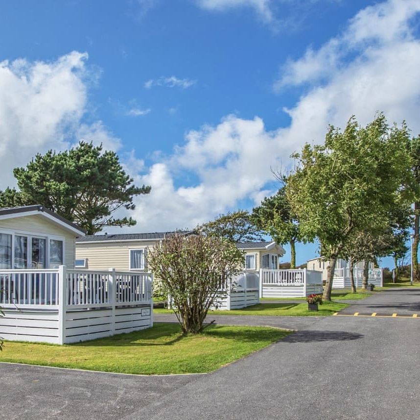 Row of holiday park caravans with white porches on a sunny day