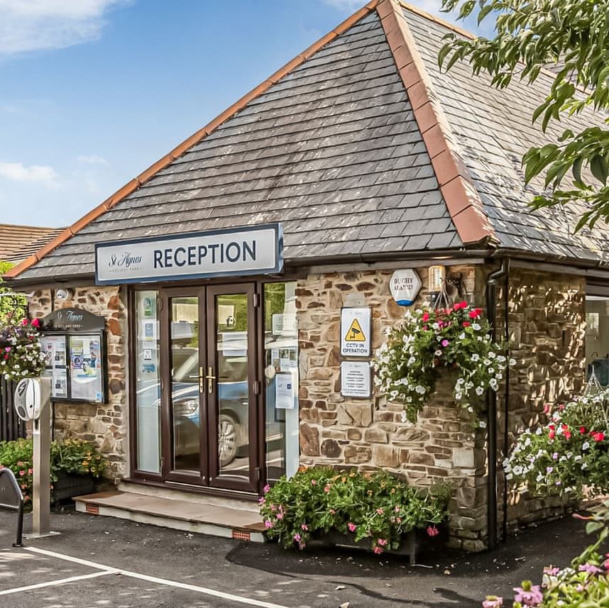 Reception building with stone exterior, hanging flower baskets, and visible signs.