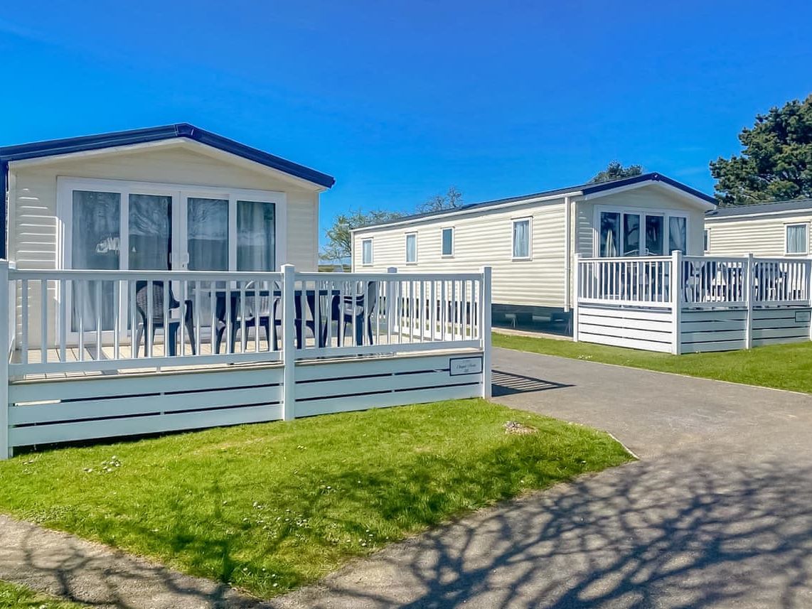 Modern mobile homes with white railings and porches on a sunny day