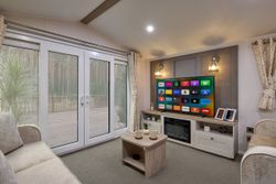 Modern living room with large windows, TV, and cozy seating