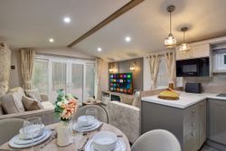 Modern open-plan living space with kitchen, dining area, and lounge in a mobile home or holiday lodge
