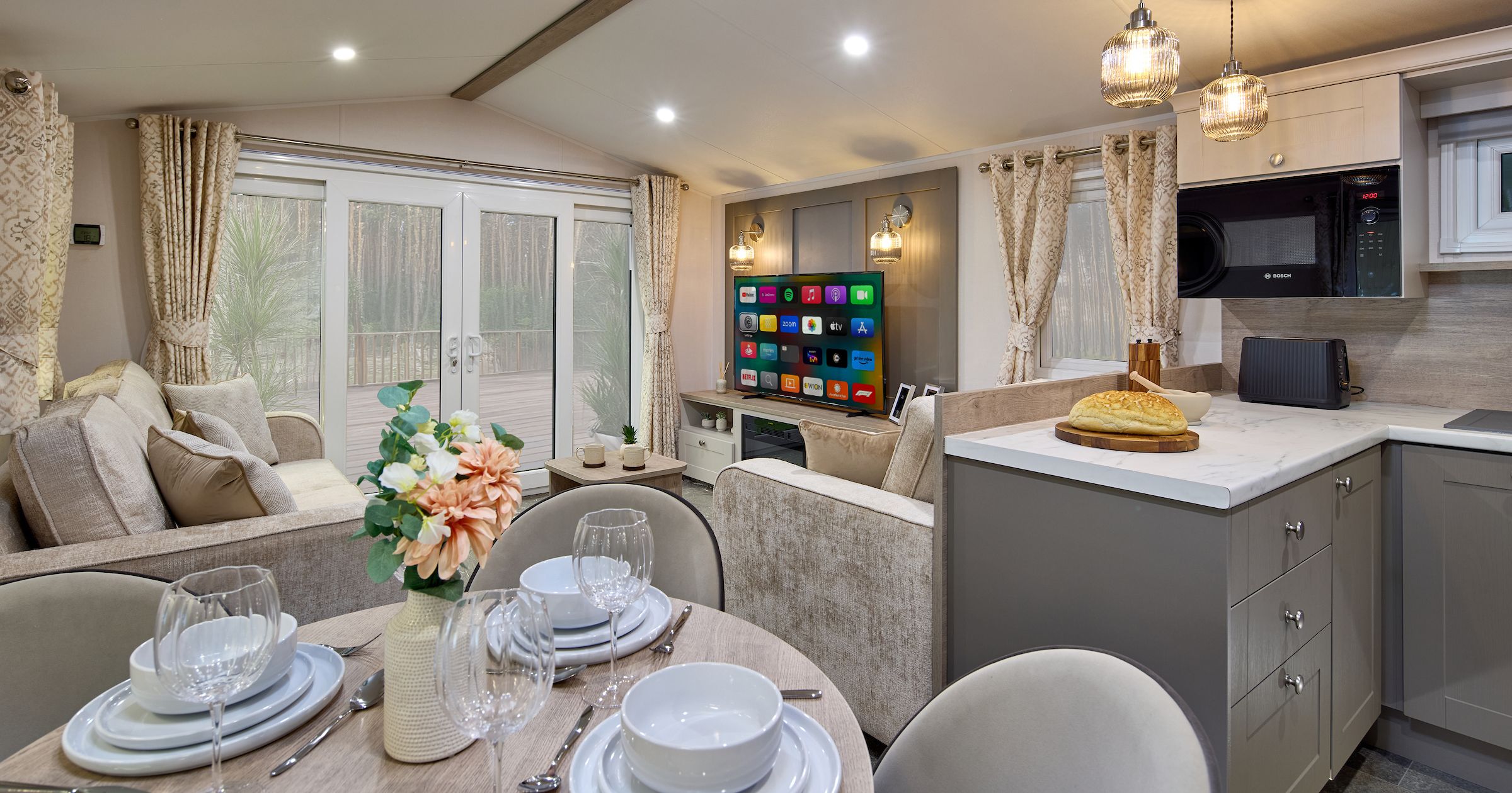 Modern open-plan living space with kitchen, dining area, and lounge in a mobile home or holiday lodge