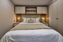 Modern bedroom with a neatly made bed, bedside tables, and wall-mounted lamps.