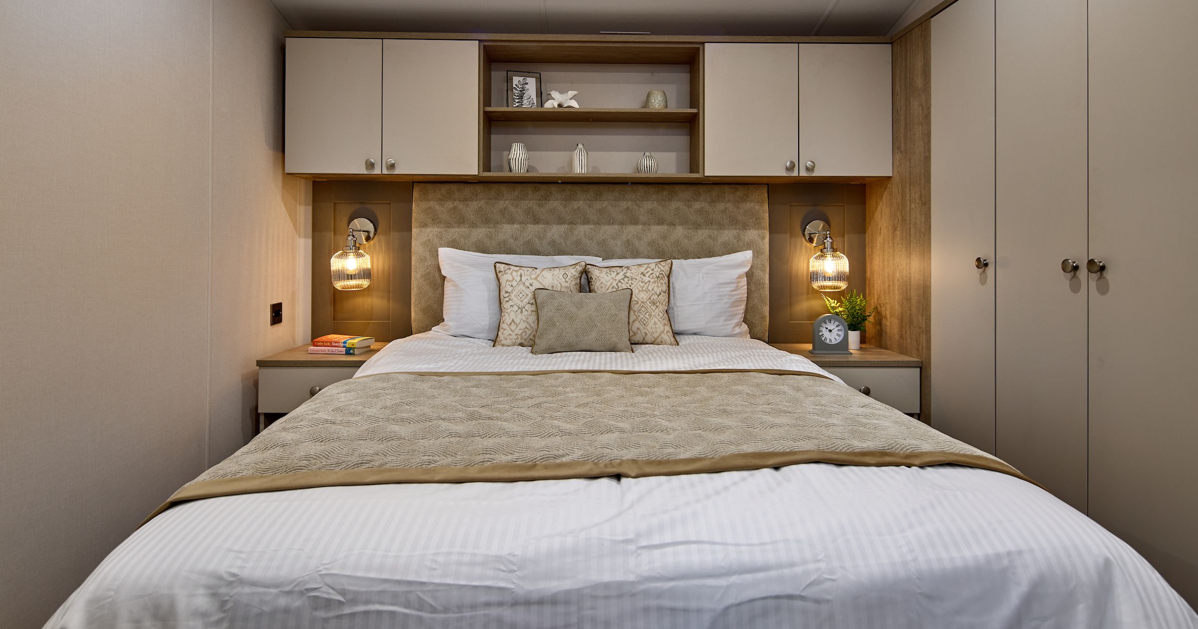 Modern cozy bedroom with bed, pillows, bedside tables, and built-in cabinets