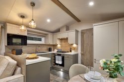 Modern kitchen with beige cabinets, pendant lights, and dining table set