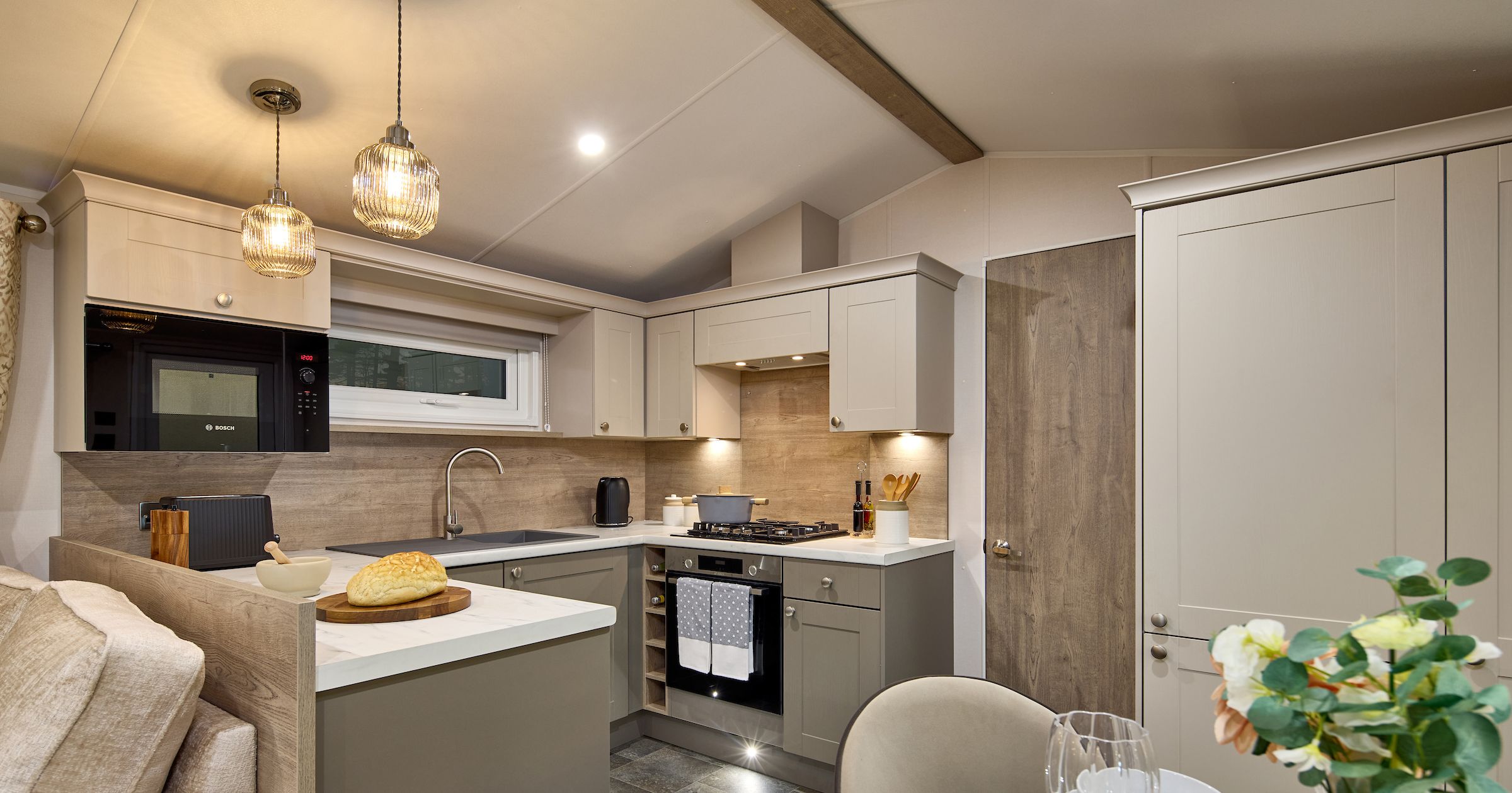 Modern kitchen with beige cabinets, pendant lights, and dining table set