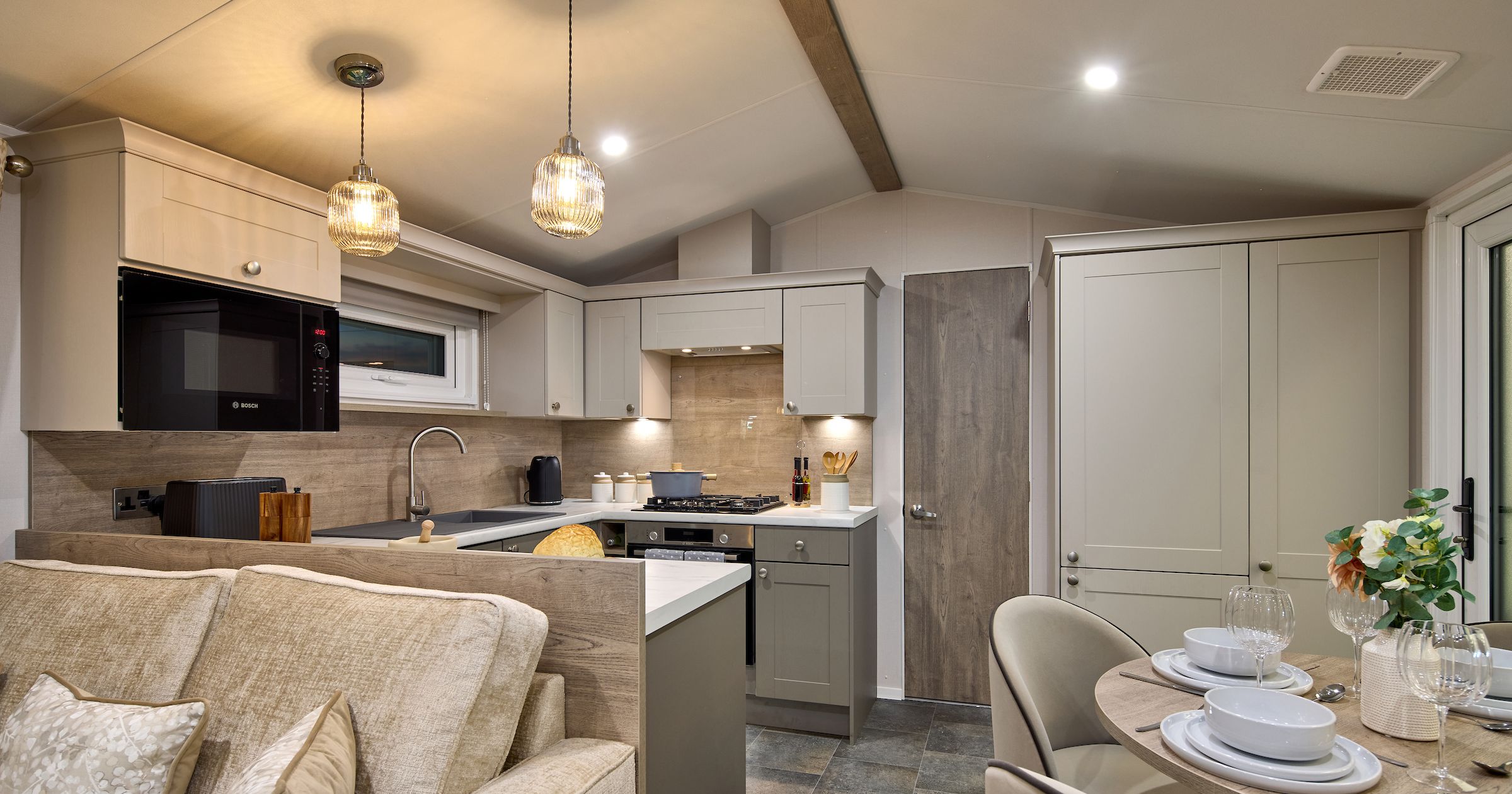 Modern kitchen and dining area with neutral tones and cozy lighting.