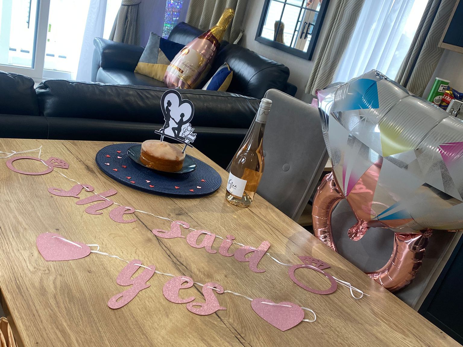 Engagement celebration setup with decorations, cake, wine, and balloons.