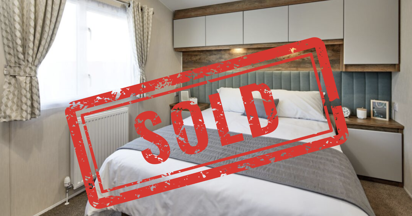 Modern bedroom with double bed, bedside tables, and overhead cabinets, with a large red 'SOLD' stamp over the image.