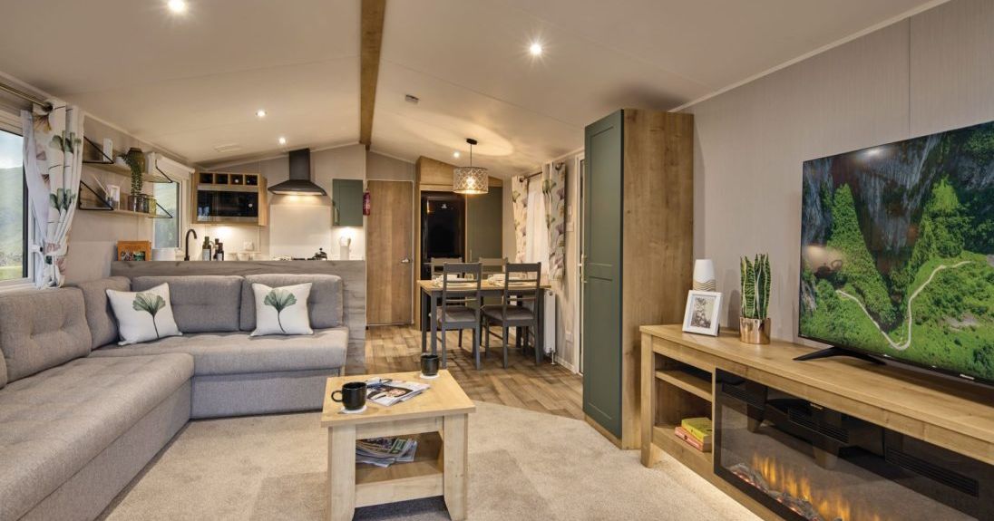 Modern living room and kitchen area in a cozy home with light wood furniture, fireplace, and large sectional sofa.