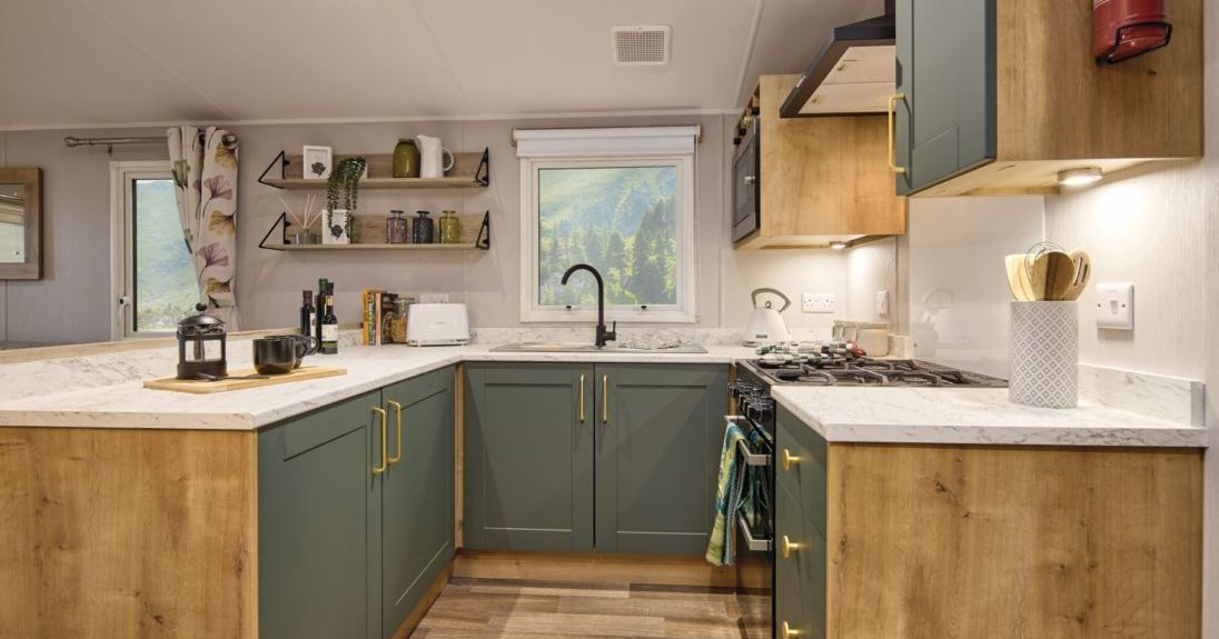 Modern kitchen with green cabinets, wood accents, and marble countertops