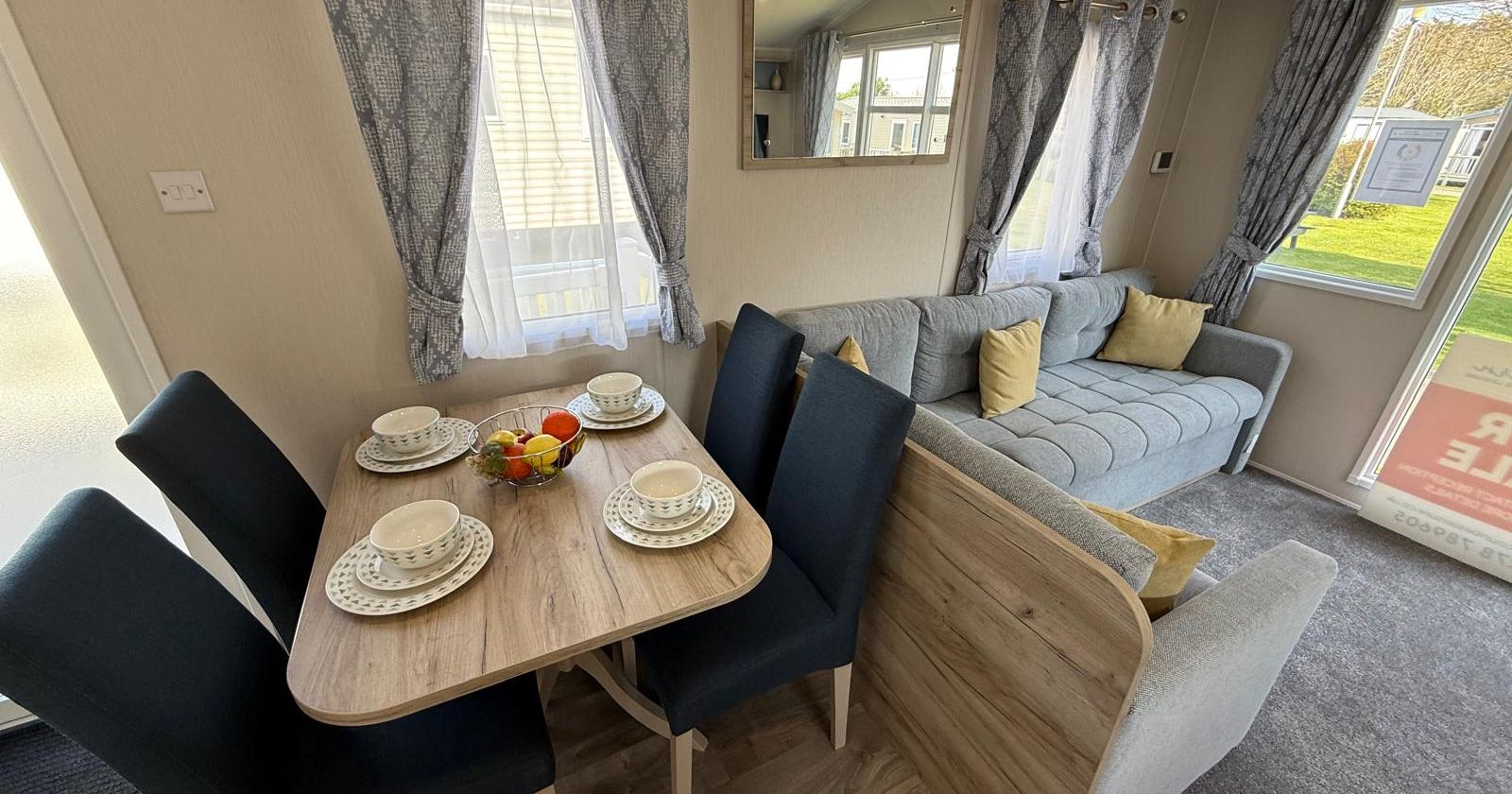 Modern living and dining area inside a caravan with a set dining table and a comfortable sofa.