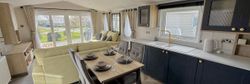 Modern open plan mobile home interior with kitchen, dining, and living area.