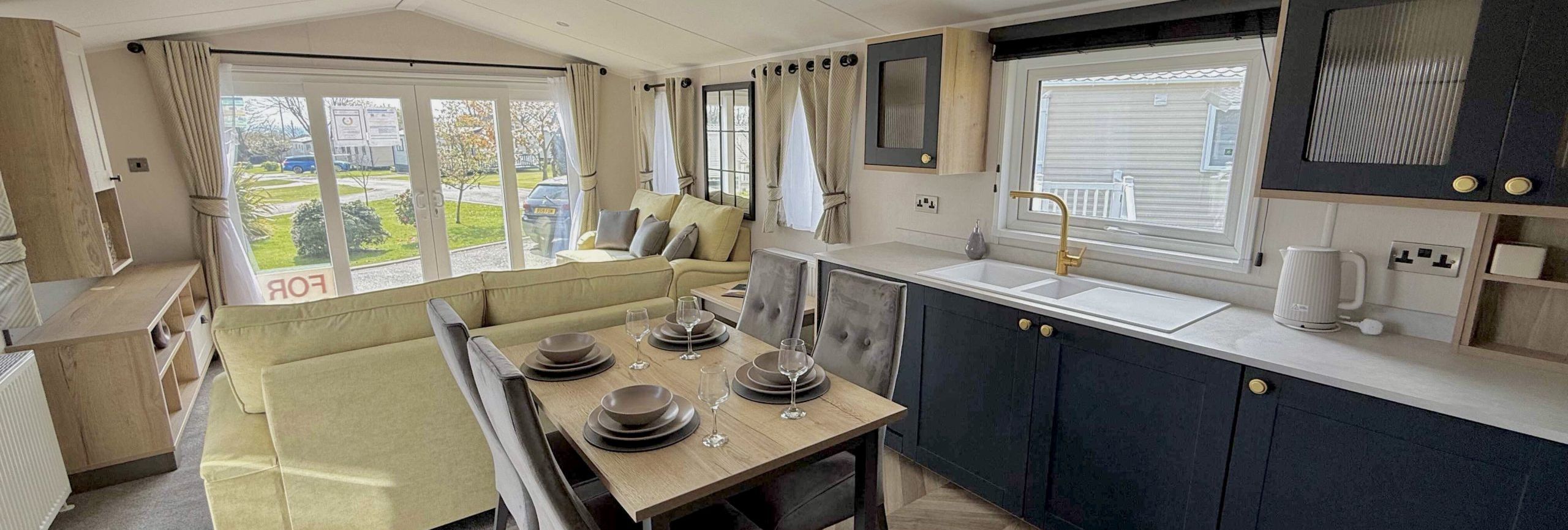 Modern open plan mobile home interior with kitchen, dining, and living area.