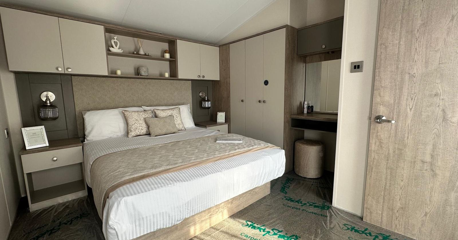 Modern neutral-toned bedroom with double bed, built-in wardrobes and dressing table