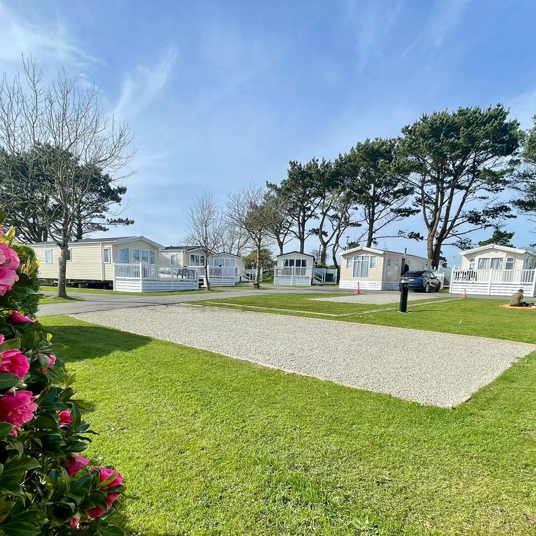Gravel pitch with motorhome beside holiday caravans on a sunny park