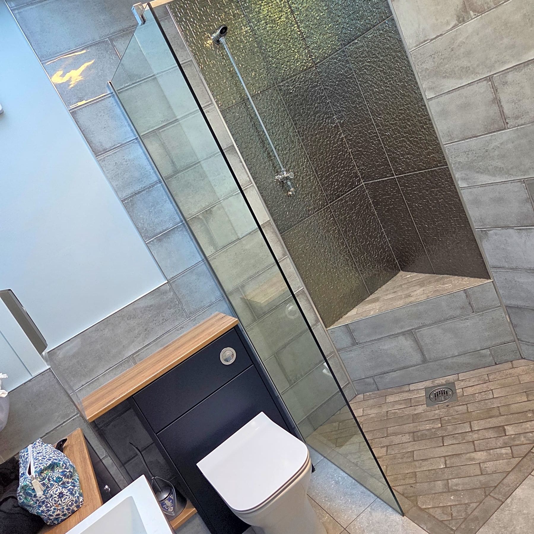 Modern bathroom with walk-in shower, grey tiled walls and white toilet