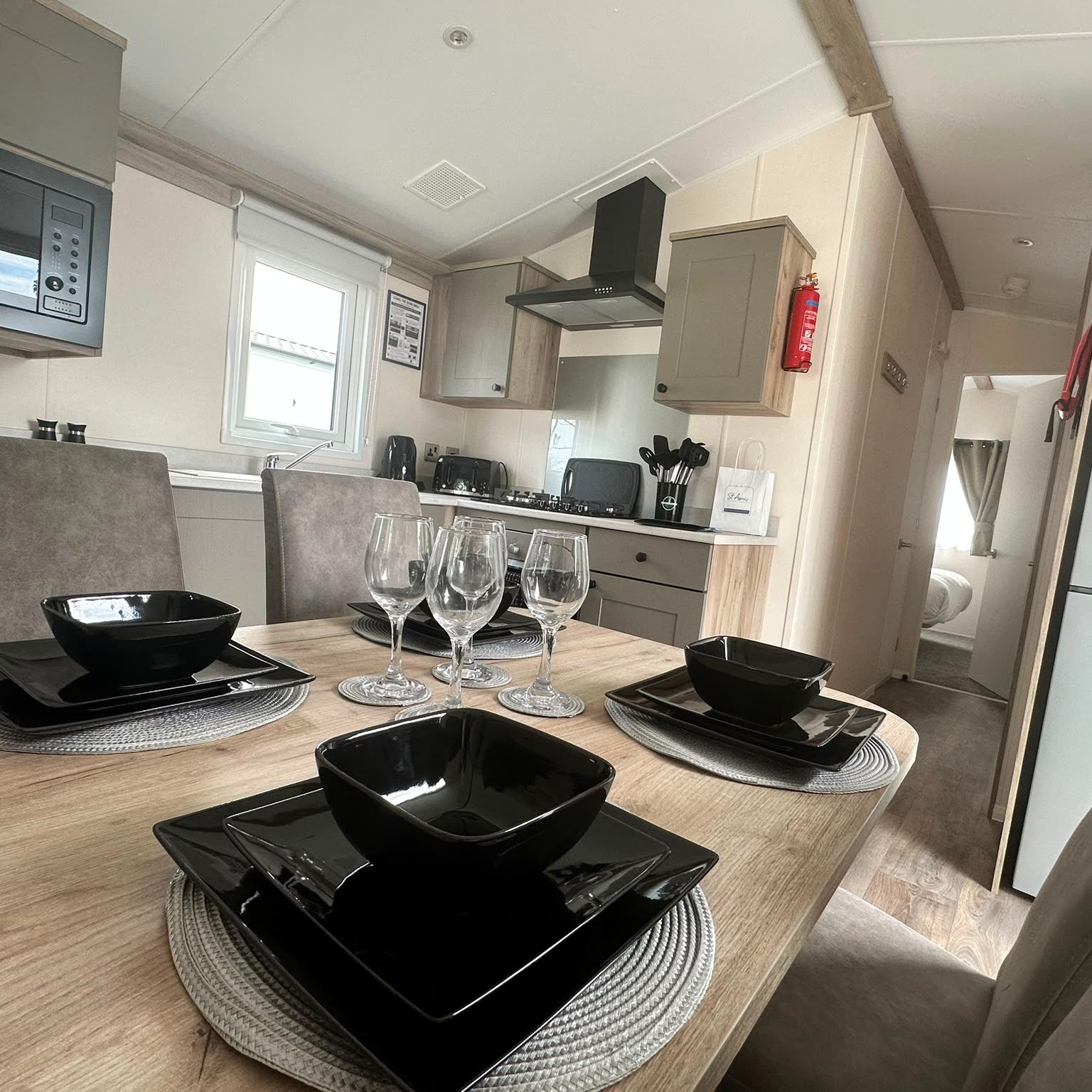 Modern caravan kitchen and dining area with set table, black dinnerware and wine glasses