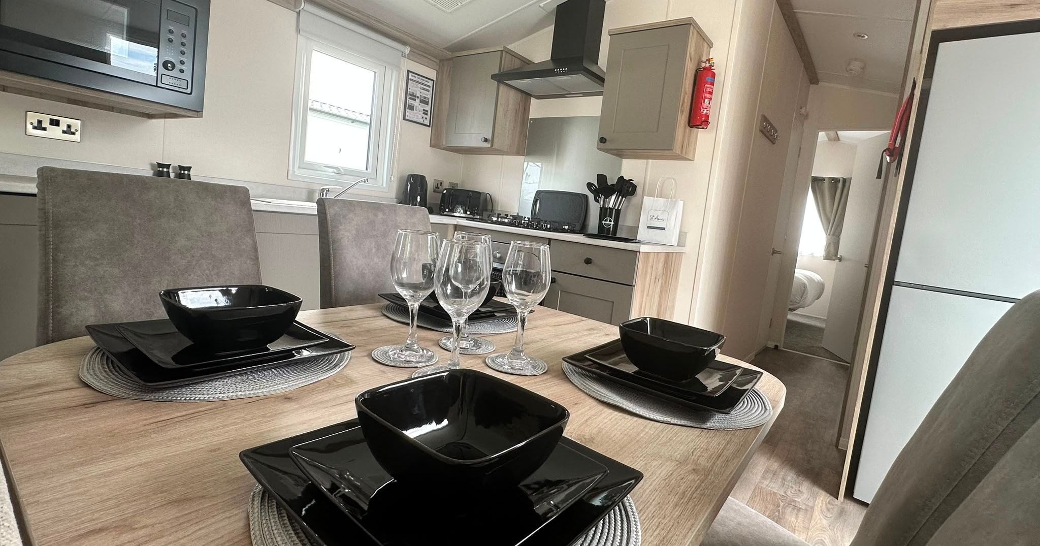 Modern caravan kitchen and dining area with set table, black dinnerware and wine glasses