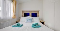Master bed room with white bed sheets and blue towels