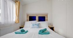 Master bed room with white bed sheets and blue towels