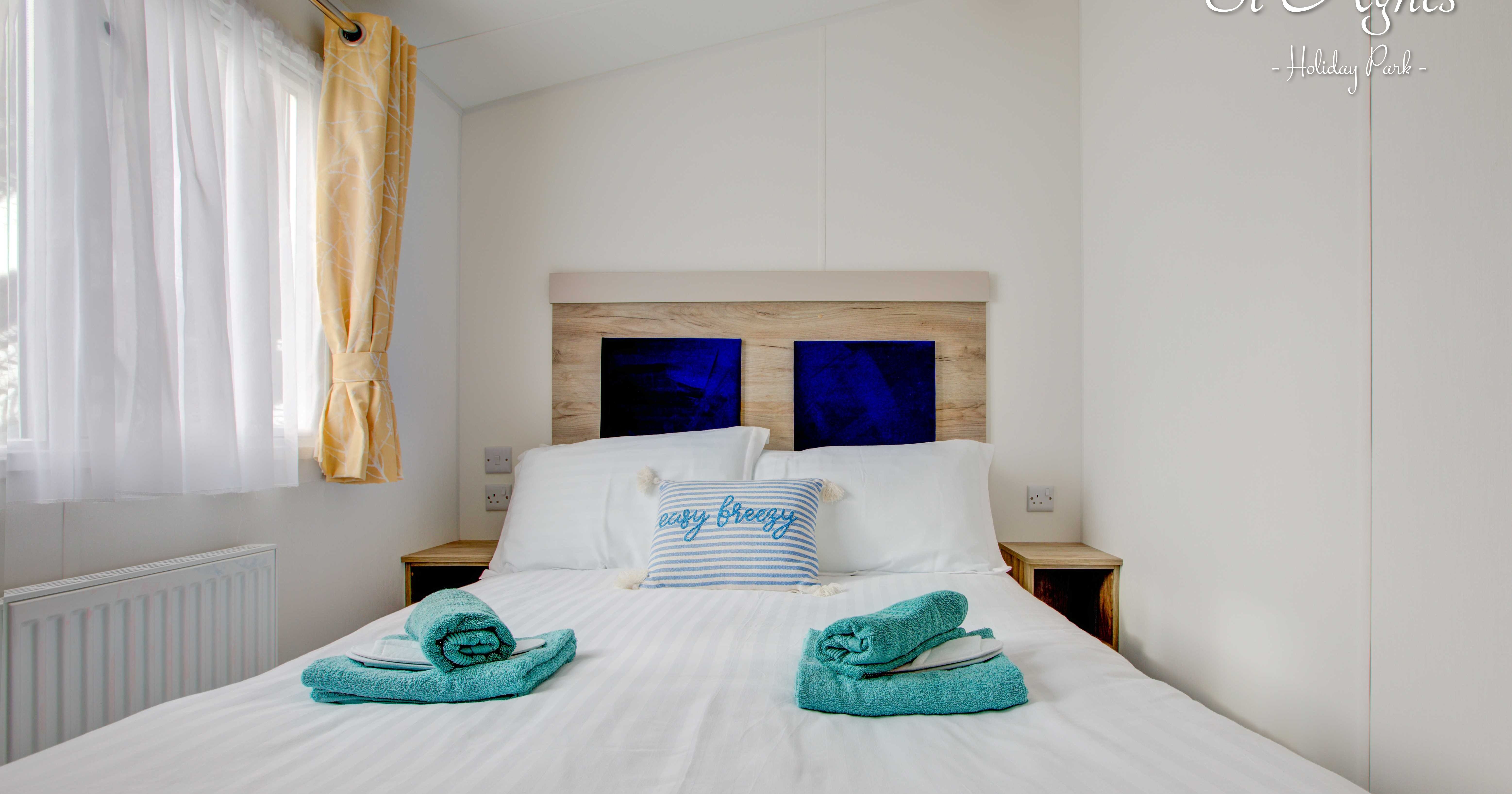 Master bed room with white bed sheets and blue towels