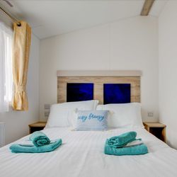 Master bed room with white bed sheets and blue towels