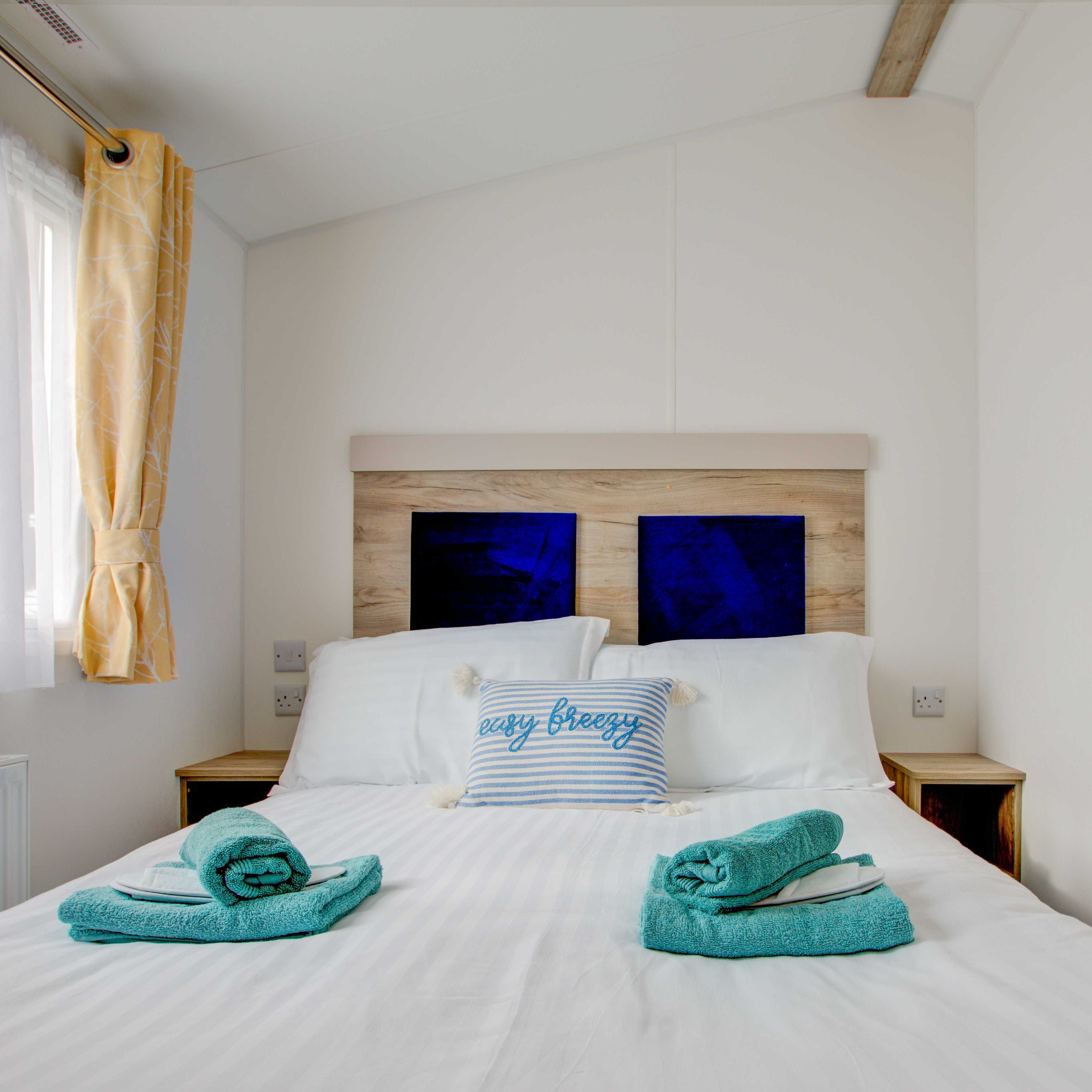 Master bed room with white bed sheets and blue towels