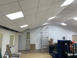 Interior of a room under construction with ladders, scaffolding, and construction materials.