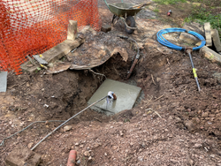 Construction site with a hole in the ground, concrete foundation, and scattered construction tools.