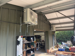 Outdoor view of workshop with two Mitsubishi air conditioning units mounted on the exterior wall