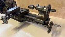 Close-up view of a metal lathe machine with detailed hand wheels and chuck.