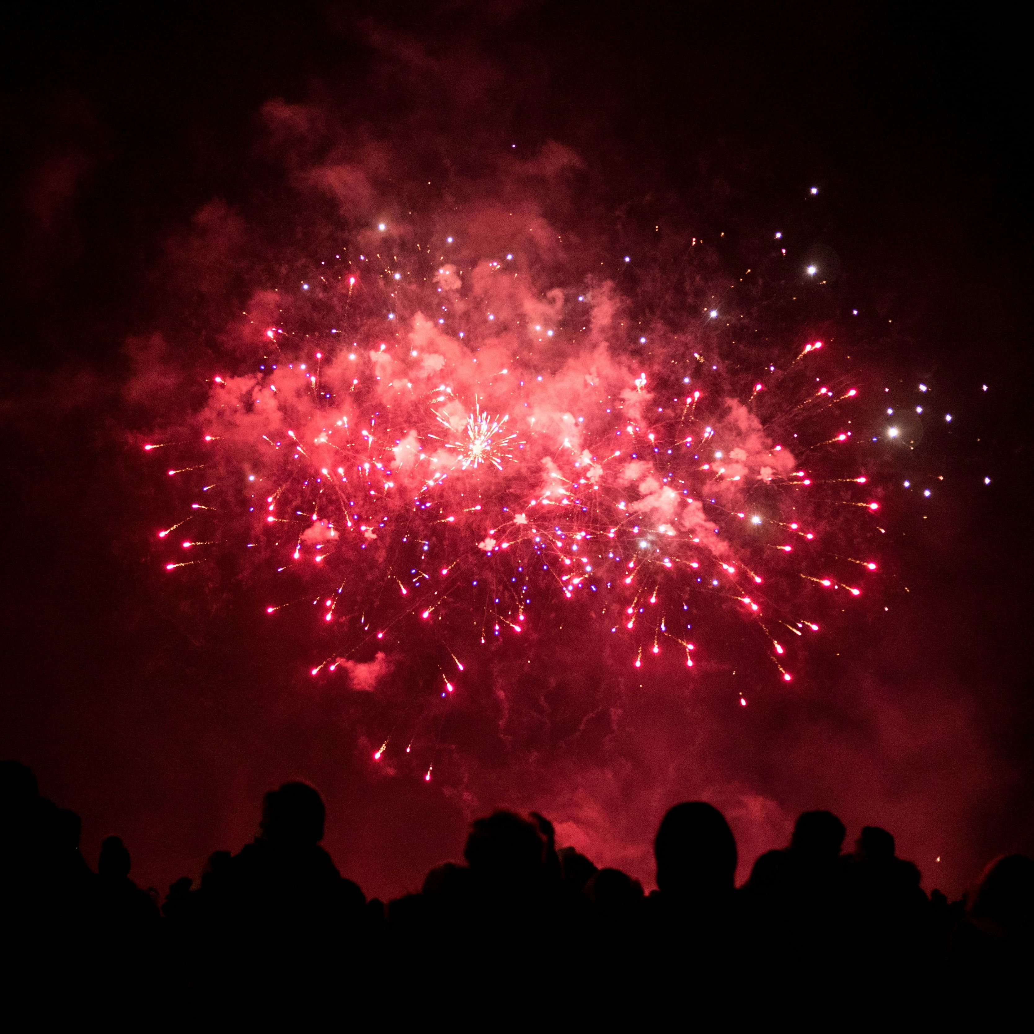 Crowd watching colorful fireworks explode in the night sky