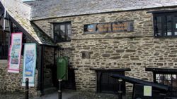 Exterior of The Old Guildhall Gaol & Museum, a historic stone building with banners and a cannon outside.