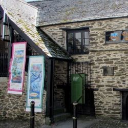 Exterior of The Old Guildhall Gaol & Museum, a historic stone building with banners and a cannon outside.