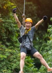 Person ziplining through lush green forest