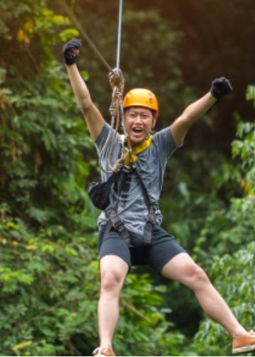 Person ziplining through lush green forest
